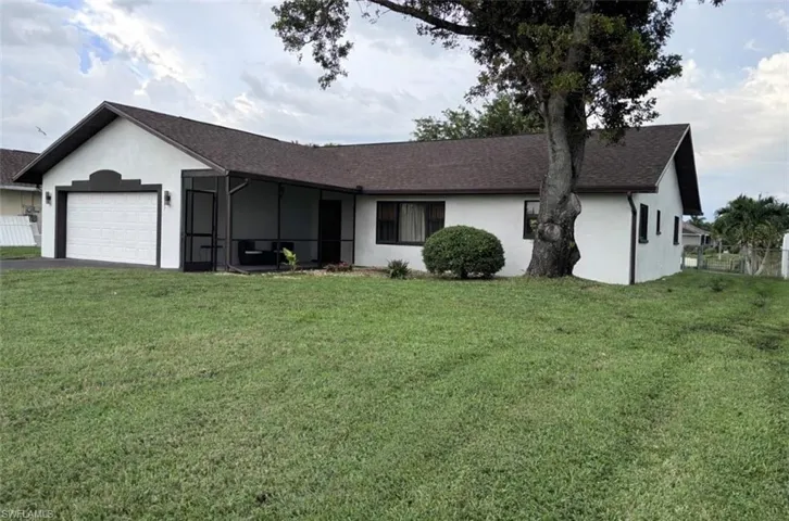 Ranch-style house with stucco siding, a sunroom, roof with shingles, and an attached garage