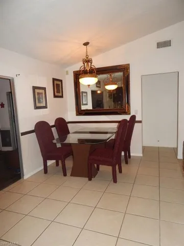 Dining area featuring light tile patterned flooring and vaulted ceiling