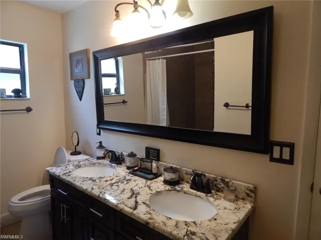 Full bathroom featuring double vanity and a shower with shower curtain