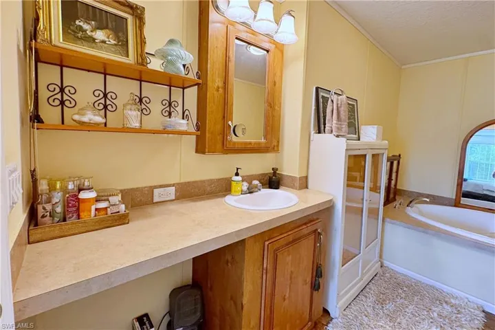 Bathroom with a bath, vanity, a textured ceiling, and ornamental molding