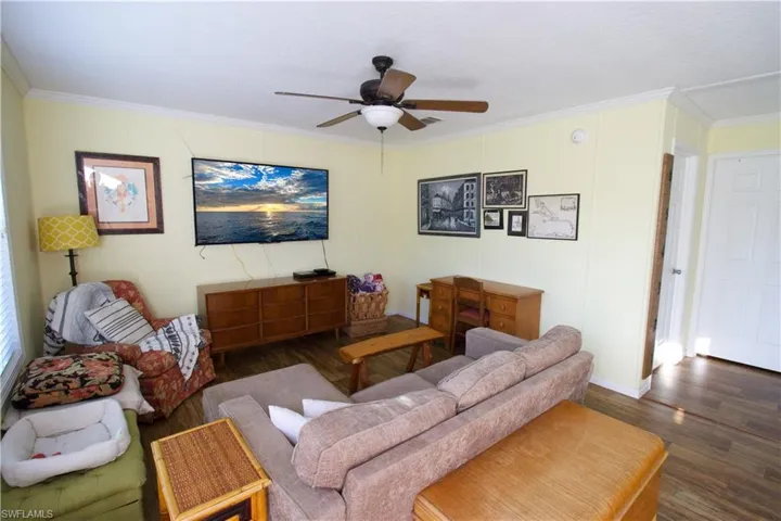 Living room featuring crown molding, dark hardwood / wood-style flooring, and ceiling fan