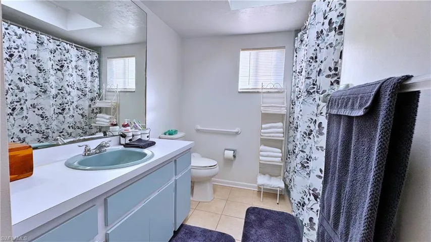 Bathroom with tile patterned flooring, vanity, toilet, and walk in shower