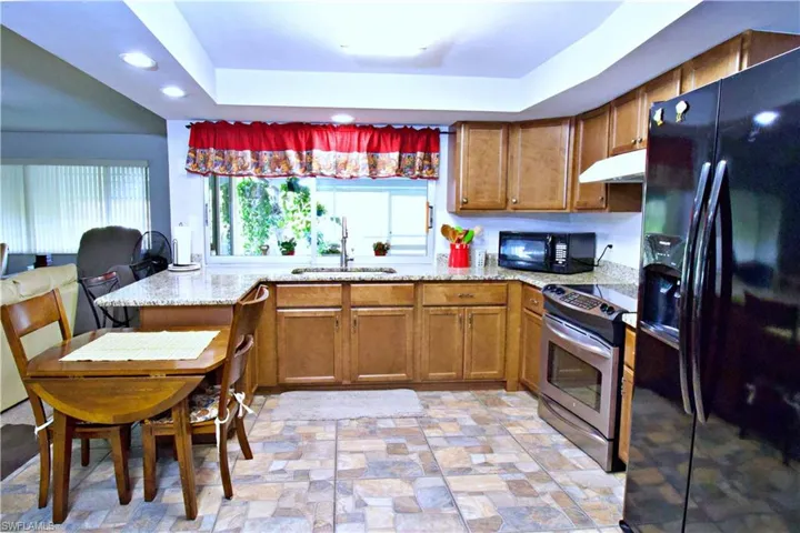 Kitchen featuring kitchen peninsula, a wealth of natural light, sink, and black appliances