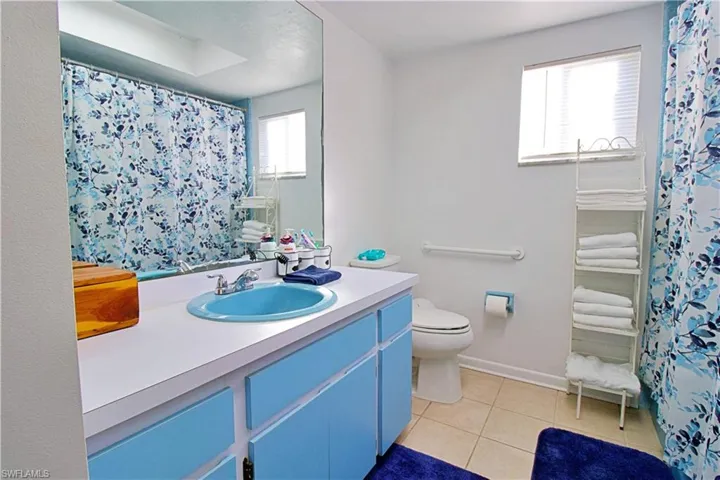 Bathroom with a shower with curtain, tile patterned flooring, vanity, and toilet