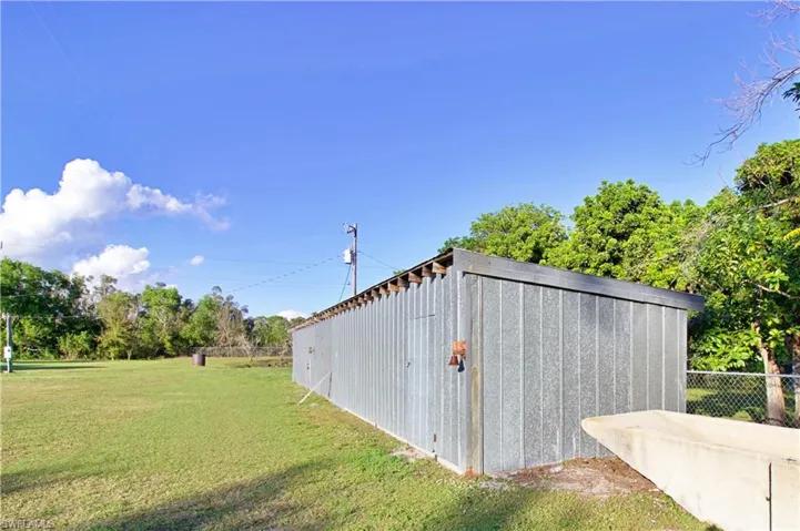 View of outdoor structure featuring a lawn