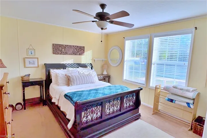 Carpeted bedroom featuring ceiling fan and multiple windows
