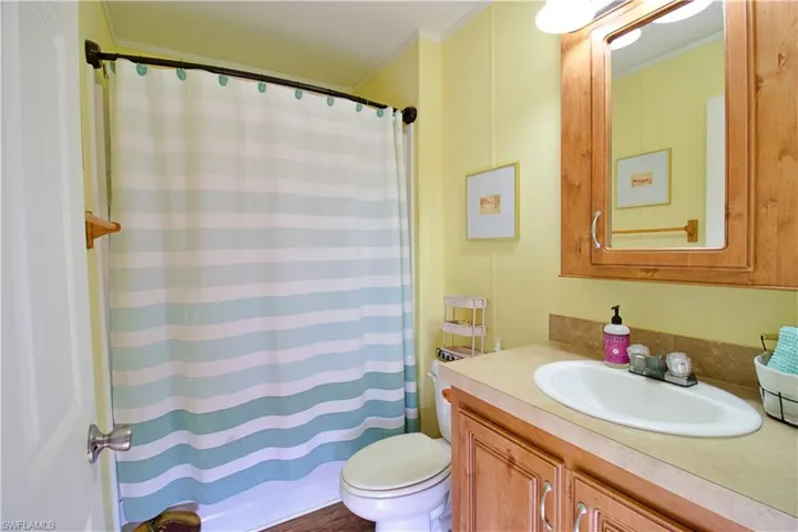 Bathroom with a shower with curtain, vanity, toilet, and crown molding