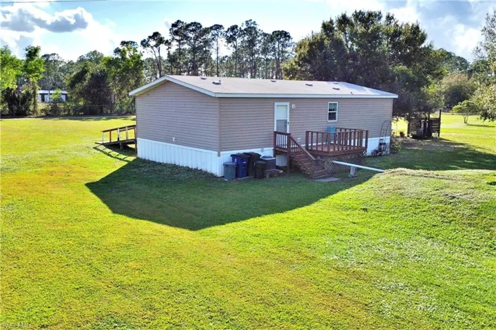 Back of house featuring a lawn and a deck