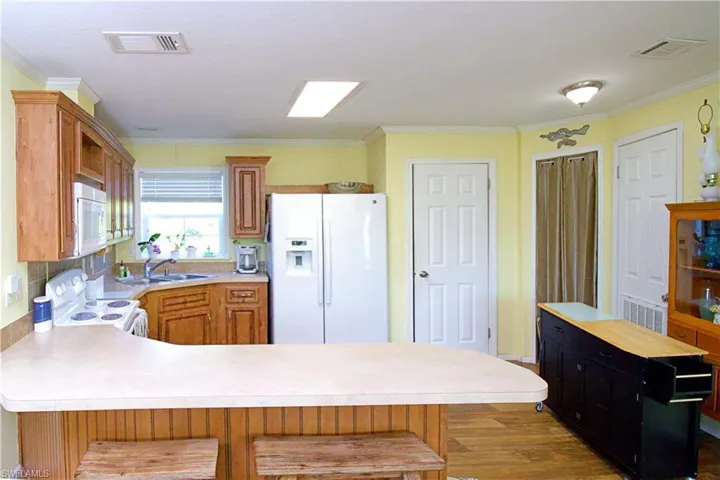 Kitchen featuring a kitchen bar, white appliances, crown molding, and sink