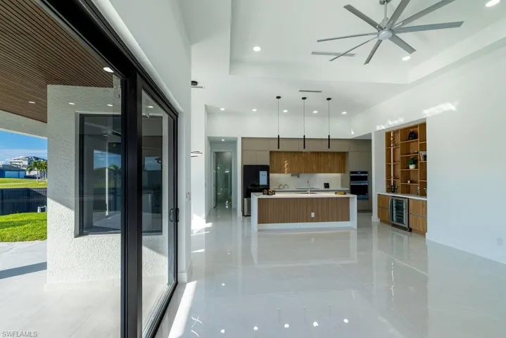 Kitchen with modern cabinets, a tray ceiling, ceiling fan, light countertops, and decorative light fixtures