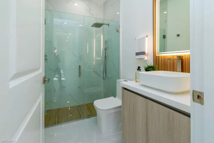 Full bathroom featuring a marble finish shower, vanity, and toilet