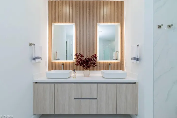 Bathroom featuring double vanity and a marble finish shower