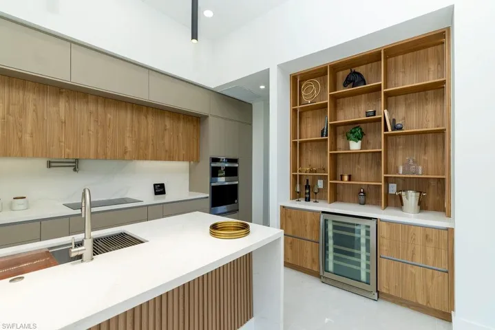 Kitchen featuring beverage cooler, modern cabinets, double oven, light countertops, and open shelves