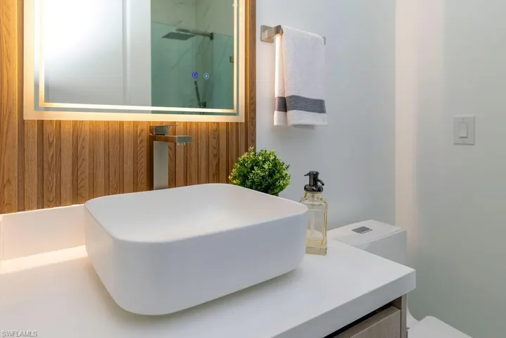 Full bath with a marble finish shower, toilet, and vanity