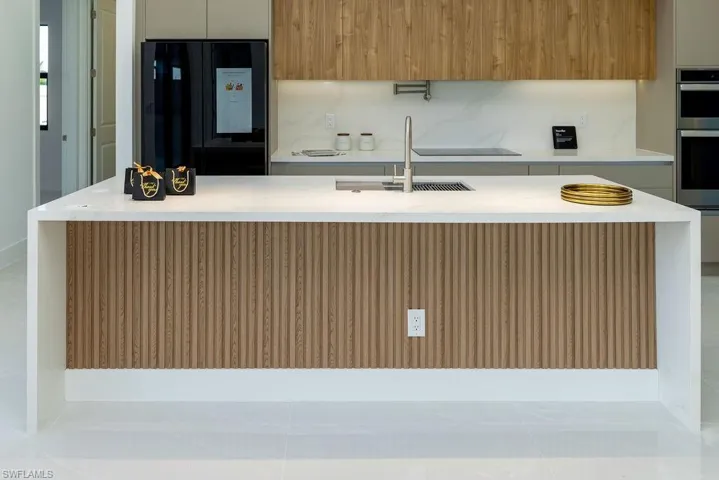 Kitchen with modern cabinets, black fridge, light countertops, a sink, and stainless steel double oven