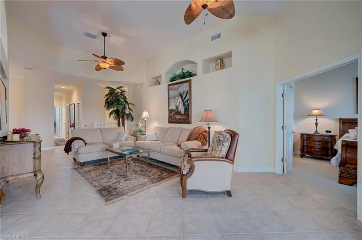 Living room with ceiling fan, light tile patterned floors, and vaulted ceiling