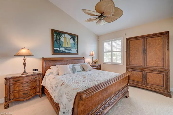 Bedroom with lofted ceiling, light colored carpet, and a ceiling fan
