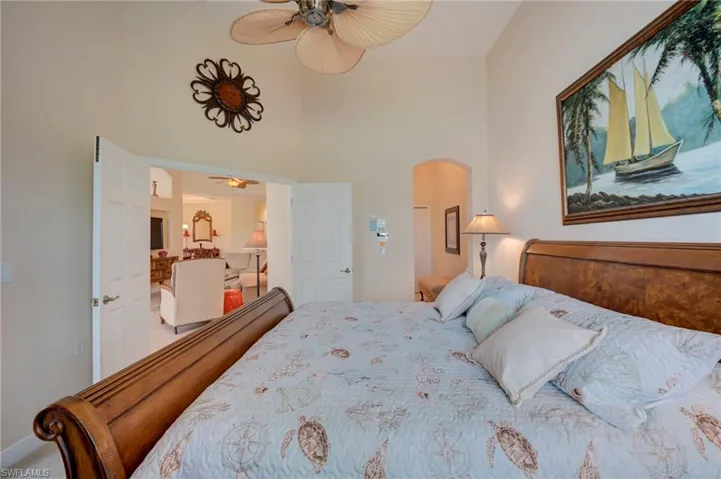 Bedroom with arched walkways, ceiling fan, and a high ceiling
