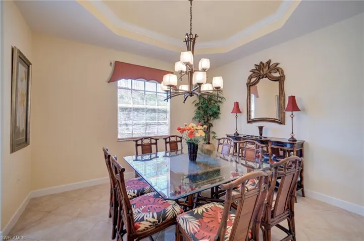 Dining room featuring crown molding, suspended lighting, a raised ceiling, and light tile patterned floors