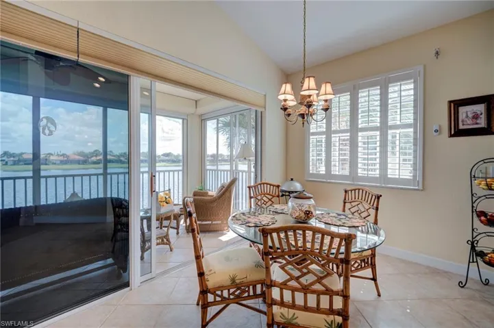 Dining space featuring a water view, vaulted ceiling, light tile patterned floors, and hanging lights