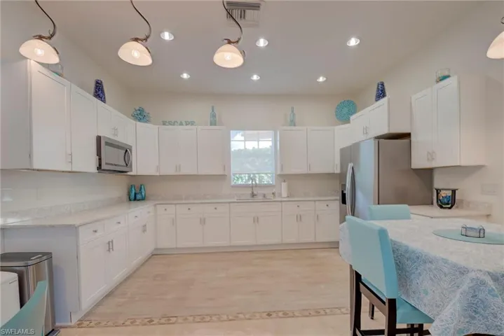 Kitchen featuring white cabinetry, stainless steel appliances, pendant lighting, and light wood-type flooring