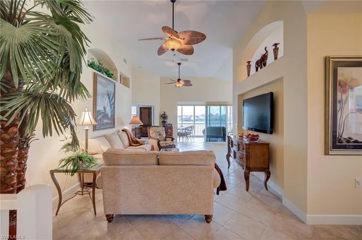 Living area with a ceiling fan, light tile patterned floors, and vaulted ceiling