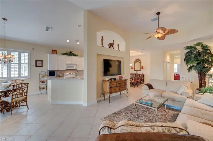 Living room featuring suspended lighting, a ceiling fan, and light tile patterned floors