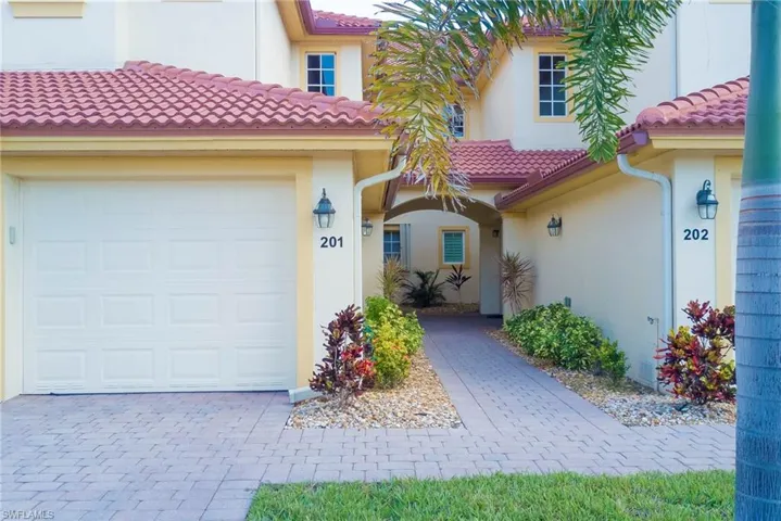 Entrance to property featuring stucco siding, a garage, a tile roof, and driveway