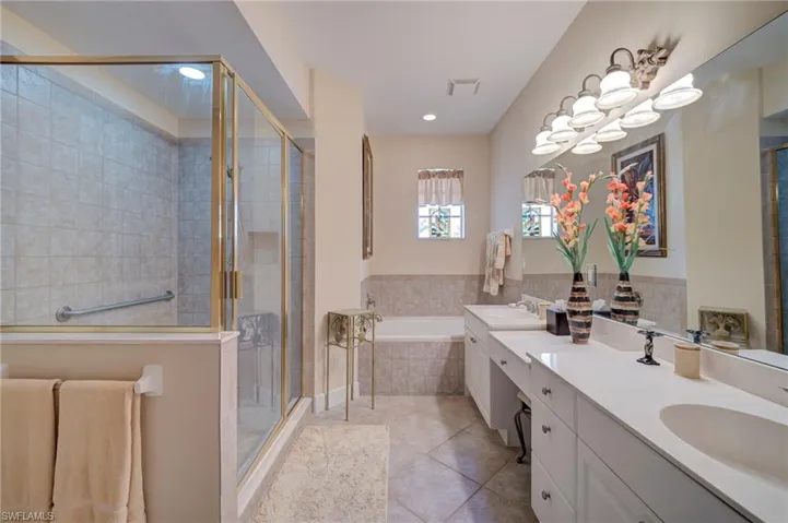 Full bath with double vanity, a stall shower, a garden tub, and light tile patterned floors