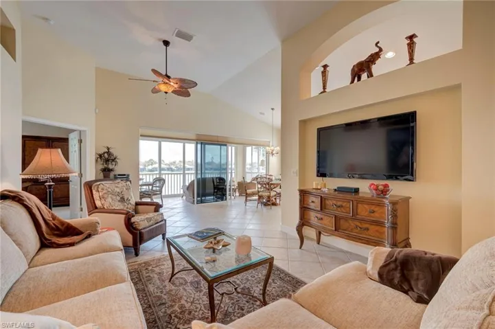 Living area featuring a ceiling fan, light tile patterned floors, vaulted ceiling, and suspended lighting
