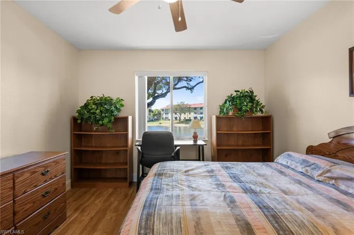 Bedroom featuring wood finished floors, ceiling fan, and a water view
