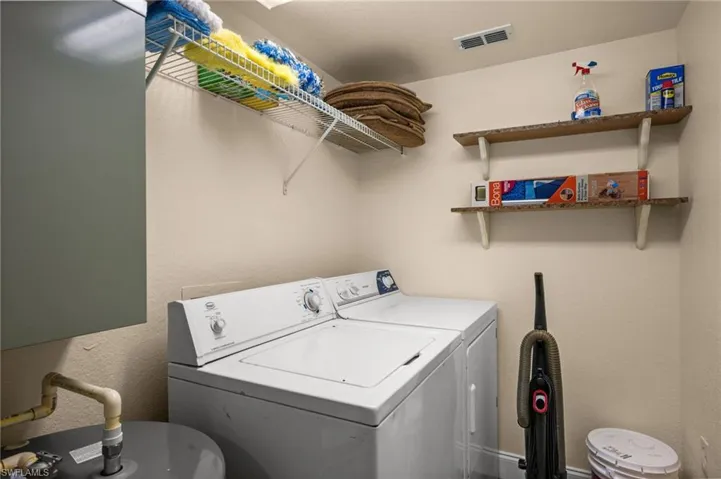 Laundry area featuring a textured wall and washing machine and clothes dryer