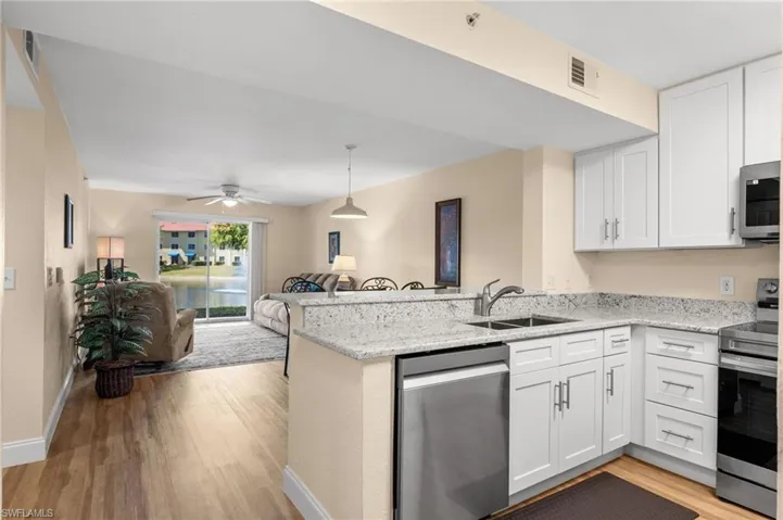 Kitchen with stainless steel appliances, light stone counters, and white cabinets