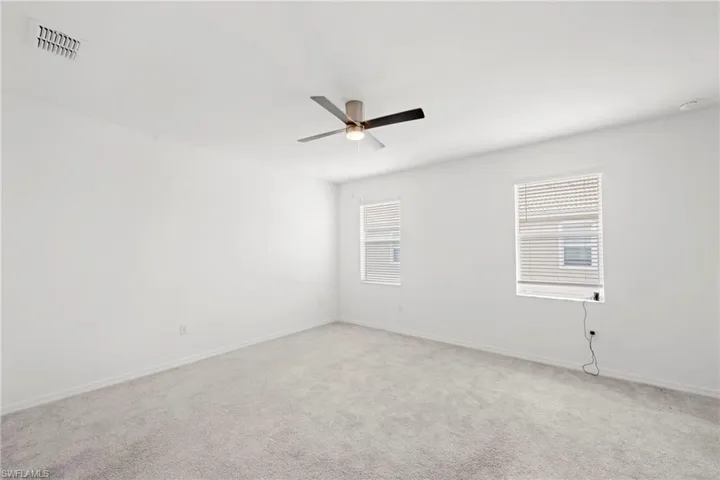Carpeted empty room featuring baseboards and a ceiling fan
