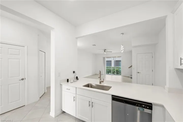 Kitchen featuring a peninsula, dishwasher, white cabinetry, a ceiling fan, and light tile patterned floors