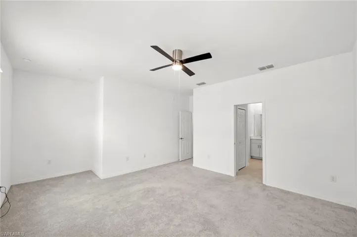 Unfurnished bedroom with light colored carpet and a ceiling fan