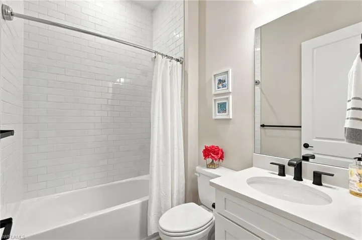 Elegantly appointed third guest bathroom featuring a shower/tub combination, white vanity, and stylish matte black fixtures, conveniently accessible to guests
