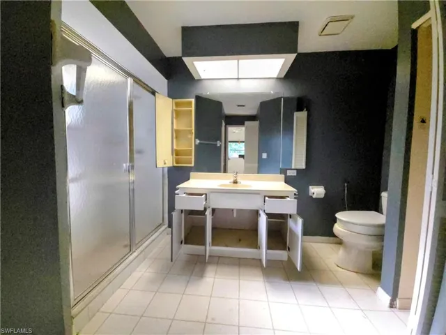 Bathroom featuring vanity, a shower stall, tile patterned floors, and a skylight