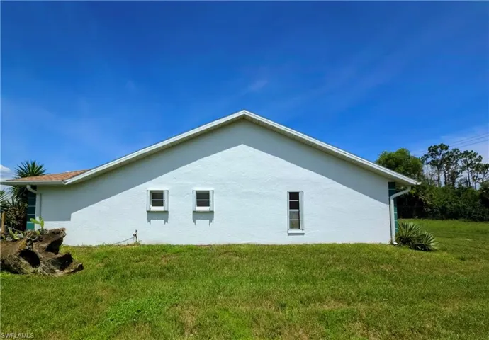 View of side of property featuring stucco siding and a yard