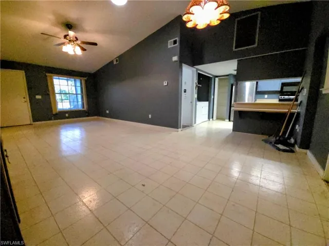Unfurnished living room featuring ceiling fan, light tile patterned flooring, and high vaulted ceiling