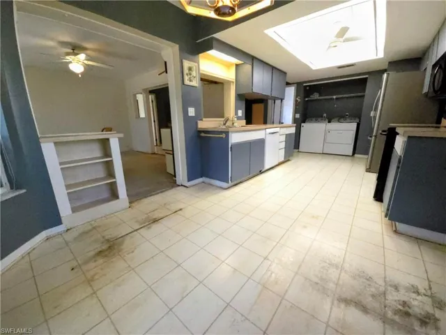 Kitchen with washer and clothes dryer, dishwasher, a ceiling fan, and light tile patterned floors
