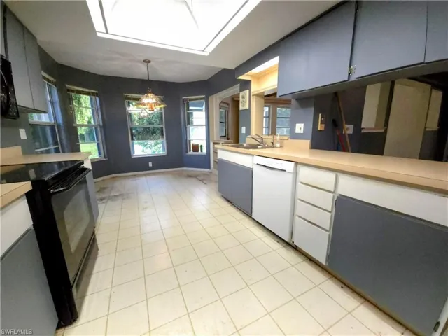 Kitchen featuring dishwasher, electric range, light countertops, light tile patterned floors, and hanging light fixtures