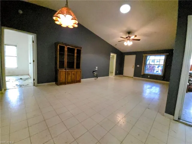 Unfurnished living room featuring vaulted ceiling, a ceiling fan, and healthy amount of natural light
