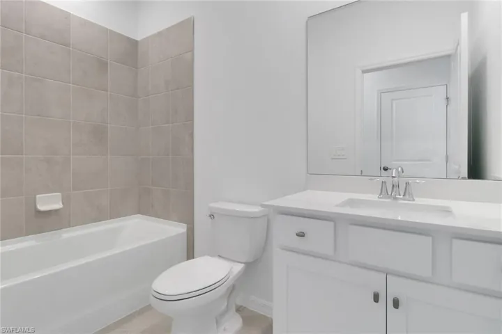 Bathroom with toilet, shower / bath combination, tile patterned flooring, and vanity