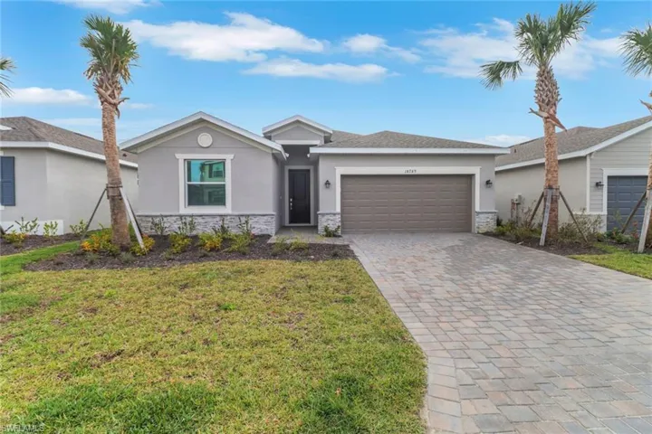 Ranch-style house with an attached garage, stone siding, a front yard, and stucco siding