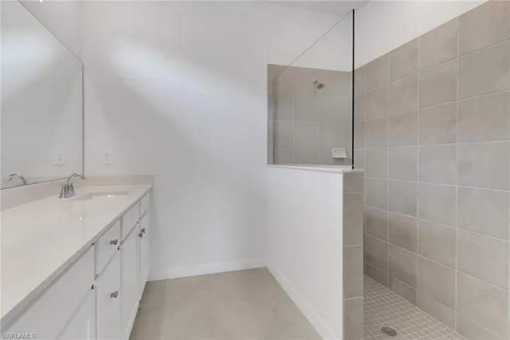 Bathroom with vanity, baseboards, and walk in shower