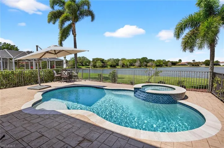 Integrated pool / hot tub with a fenced backyard, a patio, outdoor dining area, and a water view