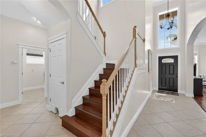 Foyer entrance with arched walkways, a high ceiling, a chandelier and ornamental molding