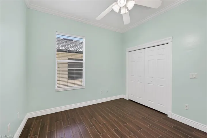 Downstairs bedroom with ornamental molding, wood finish floors