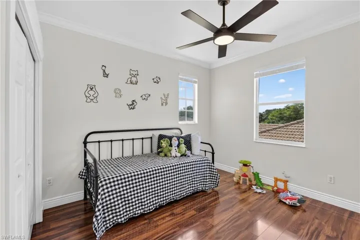 Bedroom featuring crown molding, dark wood-style flooring, a closet, and updated ceiling fan